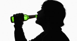 A silhouetted man drinking beer from a bottle